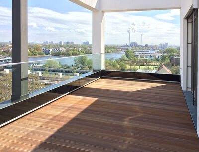 Blick von einer modernen Terrasse mit Glasgeländer von Glas Marte auf eine Flusslandschaft.