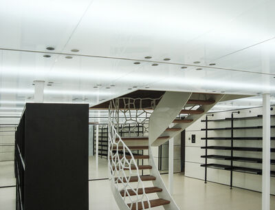 Treppenhaus mit einer wellenförmigen Metallgeländestruktur.