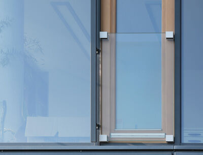 Nahaufnahme eines modernen Fensters mit Holzrahmen und einem transparenten Glasgeländer als Absturzsicherung.