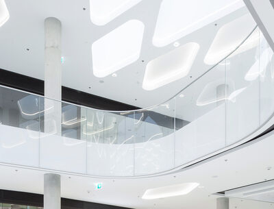 Ein heller Innenraum mit einer geschwungenen Glasbrüstung und minimalistischen Designelementen. 
